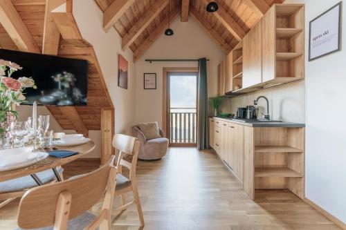 a kitchen and dining room with a table and chairs and a kitchen with wooden ceilings at Apres Ski Bachleda - LoftAffair Collection in Zakopane