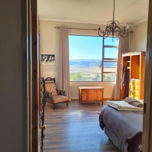 a bedroom with a bed and a window and a chair at The Fat Mulberry Guest Farm in Fouriesburg