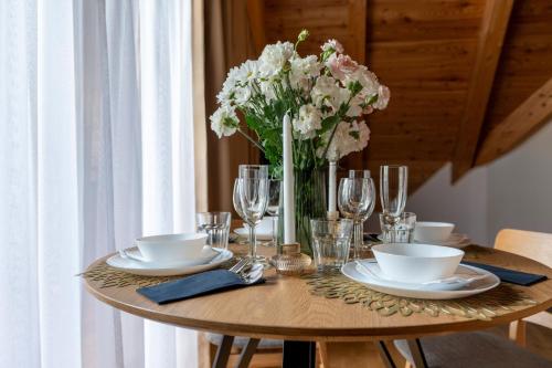 a wooden table with a vase of flowers on it at Apres Ski Bachleda - LoftAffair Collection in Zakopane