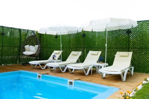 a group of chairs and an umbrella next to a pool at mutlu ve huzur dolu bir tatil in Ortaca