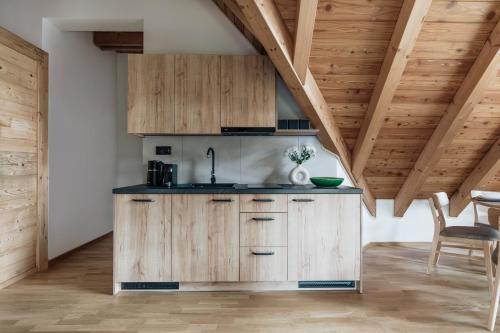 a kitchen with wooden cabinets and a wooden ceiling at Apres Ski Bachleda - LoftAffair Collection in Zakopane