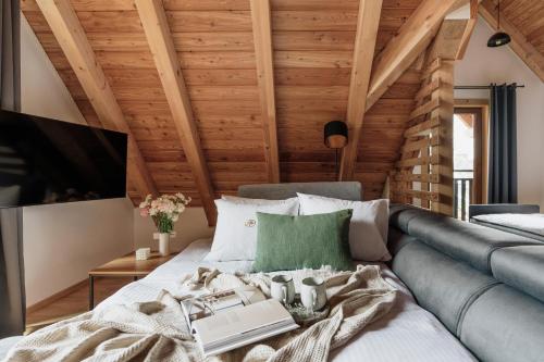 a bedroom with wooden ceilings and a couch at Apres Ski Bachleda - LoftAffair Collection in Zakopane