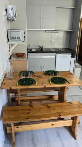 une table en bois avec quatre assiettes vertes dans la cuisine dans l'établissement Résidence Rond-point-pistes I - Mini studio 19m² au centre station à Orcières Merlette - Alpes du Sud MAE-7134, à Orcières