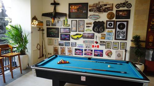 a room with a pool table and a wall with pictures at BAGUS Guest House in Legian