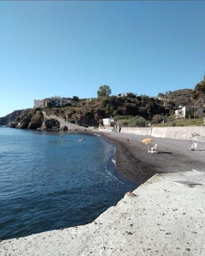 a beach with chairs and an umbrella and the water at Itaca in Lipari