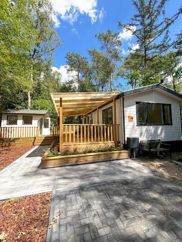 a tiny house with a porch and a deck at Bosrijk chalet Veranda, Honden in Doornspijk