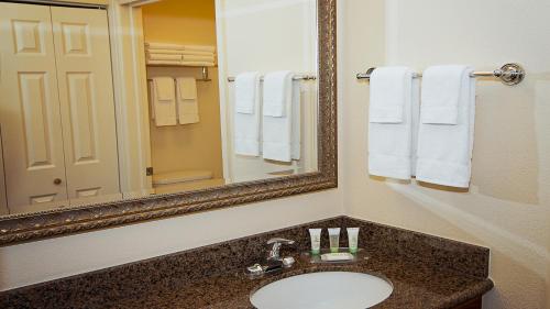 a bathroom with a sink and a mirror and towels at Staybridge Suites Wichita, an IHG Hotel in Wichita
