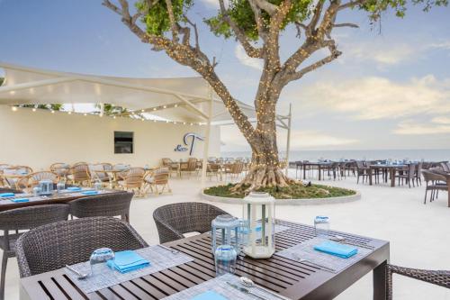 a restaurant with tables and chairs and a tree at Aviyana Hua Hin in Cha Am