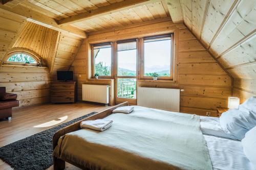 a bedroom with a large bed in a wooden house at VisitZakopane - Willa Karina in Witów