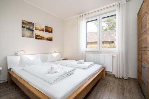 a white bedroom with a large bed with white sheets at Strandhaus-1-EG in Marienfelde
