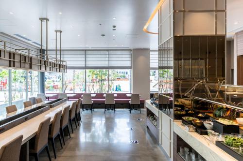 a dining room with a long counter with chairs at HOTEL TORIFITO KANAZAWA in Kanazawa