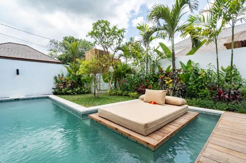 een bed op een houten platform naast een zwembad bij Villa Lounes 1 - Walking Distance to Nyanyi Beach in Tanah Lot