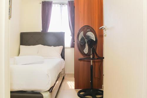 ein Schlafzimmer mit einem Bett und einem Ventilator neben einem Fenster in der Unterkunft Comfortable and Homey 3BR at Meikarta Apartment By Travelio in Cikarang