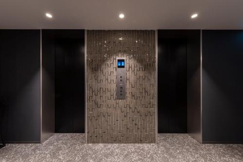 a elevator in a building with a tile wall at HOTEL TORIFITO KANAZAWA in Kanazawa
