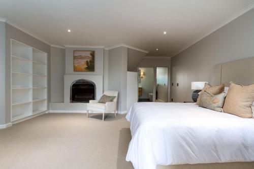a bedroom with a large white bed and a fireplace at Bay Haven Collection in Cape Town
