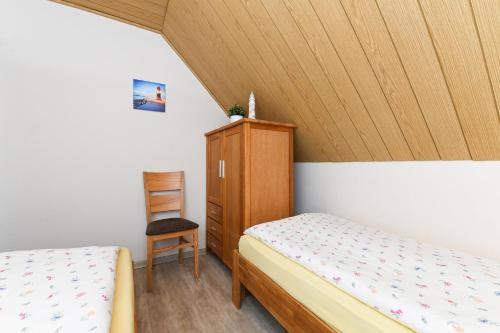 1 Schlafzimmer mit 2 Betten, einem Schrank und einem Stuhl in der Unterkunft Ferienwohnungen im Haus Friedeburg in Carolinensiel