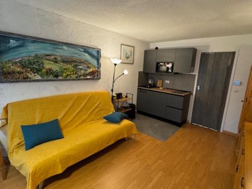 un salon avec un canapé jaune et une cuisine dans l'établissement Studio charmant proche pistes et commerces avec parking, balcon, animaux acceptés - FR-1-445-210, à Montgenèvre
