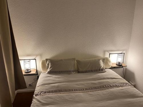 - une chambre avec un lit blanc et 2 lampes dans l'établissement Appartement moderne situé au pied des pistes, à Saint-Aventin