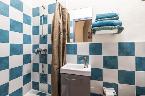 La salle de bains est pourvue de murs carrelés bleus et blancs et d'un lavabo. dans l'établissement Comédie 2 - Appt en plein centre de Perpignan, à Perpignan