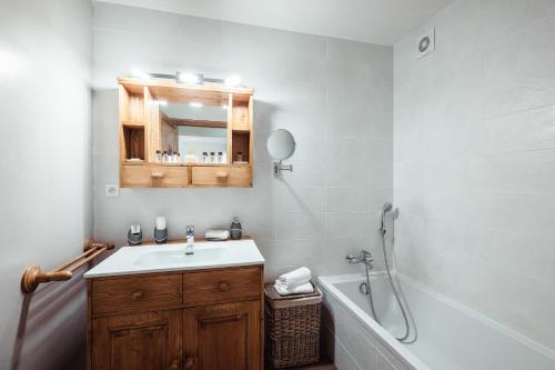 une salle de bain avec un lavabo, une baignoire et un miroir dans l'établissement Apartment - Le Cerf Blanc, à Praz-sur-Arly