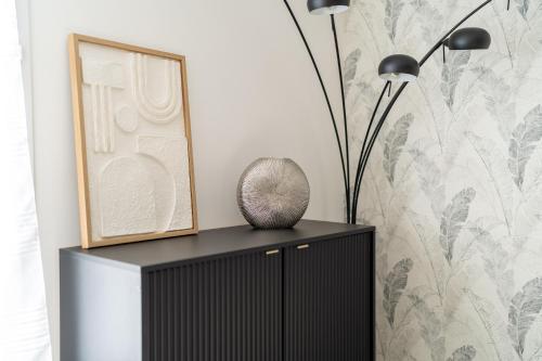 a black cabinet with two lamps and a picture at Apart' MIN - Disneyland Paris - 3 Bedrooms - 2 Parking Spots in Bailly-Romainvilliers