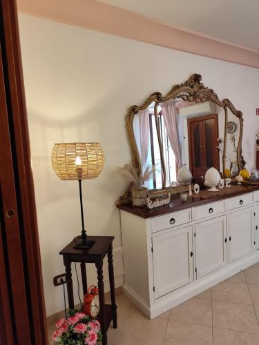 a bathroom with a mirror and a lamp on a table at Stella House in Fasano