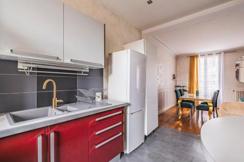 une cuisine avec des armoires rouges et un réfrigérateur blanc dans l'établissement Spacieux Cœur de Reims, à Reims
