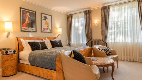 a bedroom with a king sized bed and chairs at Southernhay House Hotel in Exeter