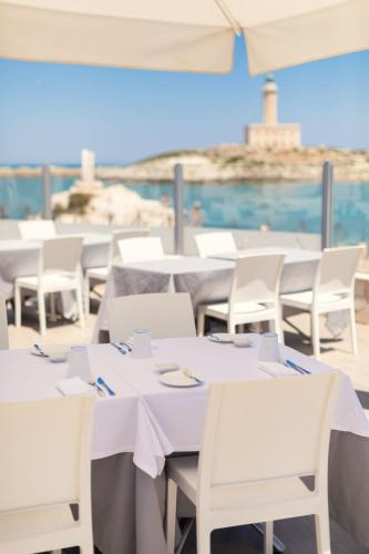 a group of tables with white chairs and an umbrella at HOTIDAY Vieste Lungomare in Vieste
