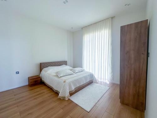 a white bedroom with a bed and a large window at White Harmony Houses in Şamaxı