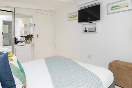 a bedroom with a bed and a tv on the wall at The Willets Boutique Hotel in Simon's Town in Simonʼs Town
