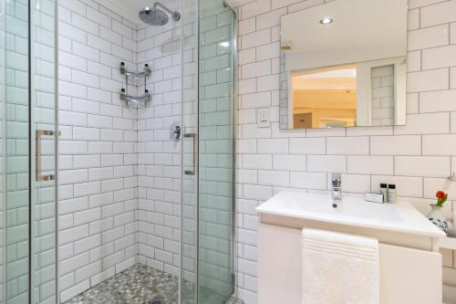 a bathroom with a shower with a sink and a mirror at The Willets Boutique Hotel in Simon's Town in Simonʼs Town