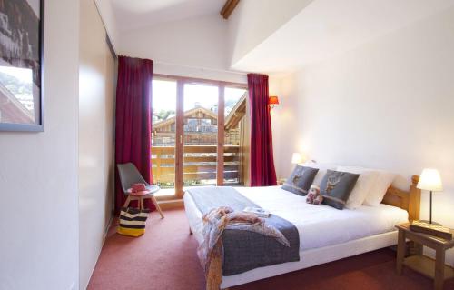 una camera da letto con un letto e una grande finestra di Résidence Odalys Les Belles Roches a Notre-Dame-de-Bellecombe