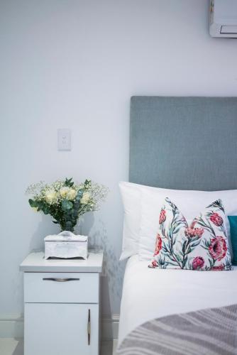 a bedroom with a bed and a vase of flowers on a night stand at The Willets Boutique Hotel in Simon's Town in Simonʼs Town