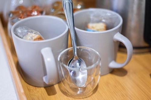 two cups with a spoon and a glass on a counter at The Willets Boutique Hotel in Simon's Town in Simonʼs Town