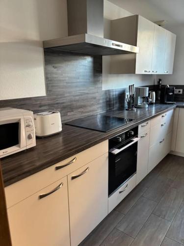 une cuisine avec des armoires blanches et un four à plaques de cuisson dans l'établissement Le grenier d Alice, à Westhouse