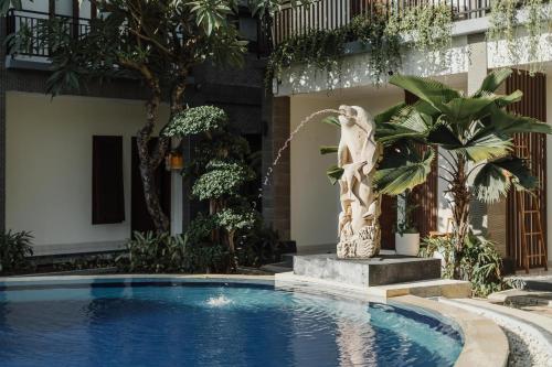 a statue next to a swimming pool with a fountain at You Suite Seminyak in Legian
