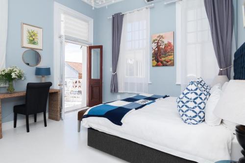 a bedroom with a bed and a desk and a window at The Willets Boutique Hotel in Simon's Town in Simonʼs Town