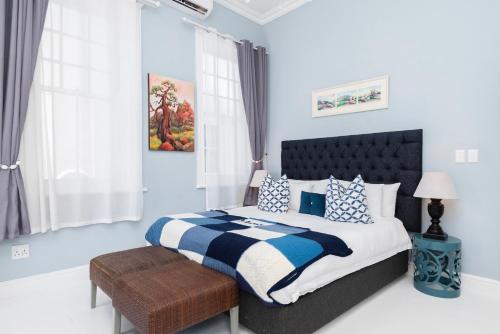 a bedroom with a large bed with blue and white pillows at The Willets Boutique Hotel in Simon's Town in Simonʼs Town