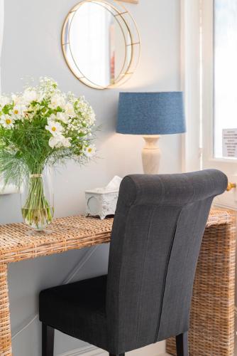 a desk with a chair and a vase of flowers at The Willets Boutique Hotel in Simon's Town in Simonʼs Town