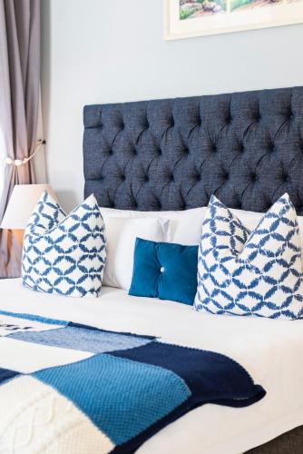 a bedroom with a bed with blue and white pillows at The Willets Boutique Hotel in Simon's Town in Simonʼs Town