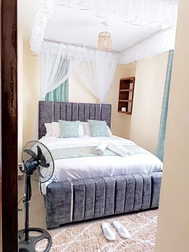 a bedroom with a large bed with a fan at Nyanchy Homes in Kisumu