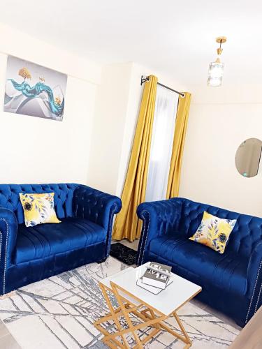 a living room with two blue couches and a coffee table at Nyanchy Homes in Kisumu