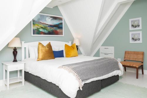 a bedroom with a large bed with yellow pillows at The Willets Boutique Hotel in Simon's Town in Simonʼs Town