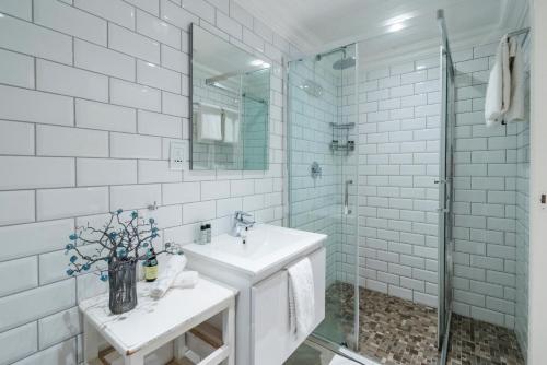 a white bathroom with a sink and a shower at The Willets Boutique Hotel in Simon's Town in Simonʼs Town