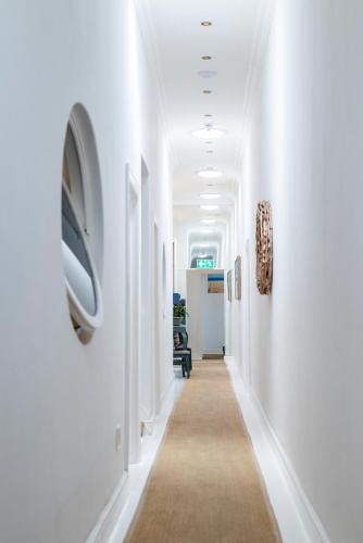 a hallway with white walls and a long hallway with a tv at The Willets Boutique Hotel in Simon's Town in Simonʼs Town