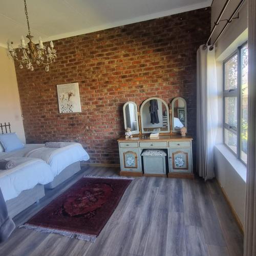 a bedroom with a bed and a brick wall at The Fat Mulberry Guest Farm in Fouriesburg