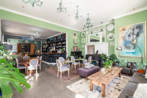 a living room with green walls and tables and chairs at The Willets Boutique Hotel in Simon's Town in Simonʼs Town