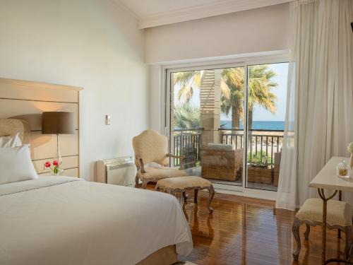 a bedroom with a bed and a view of the ocean at Grecotel Creta Palace in Rethymno Town