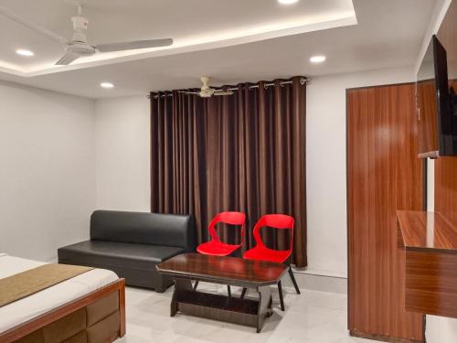 a bedroom with a bed and a desk and two red chairs at Hotel Shiv in Indore